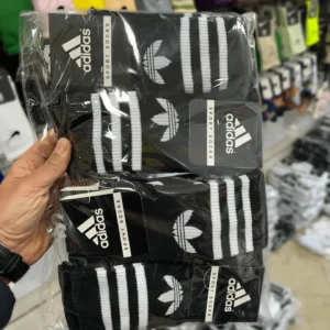 یک جین جوراب ساقدار اسپرت طرح آدیداس سه خط مشکی در دست
